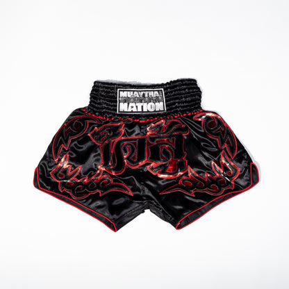 A pair of Muay Thai shorts featuring a satin fabric with a red, green, and white color scheme. The shorts have floral patterns and text that reads 'Muay Thai Nation' and 'BANGKOK'.