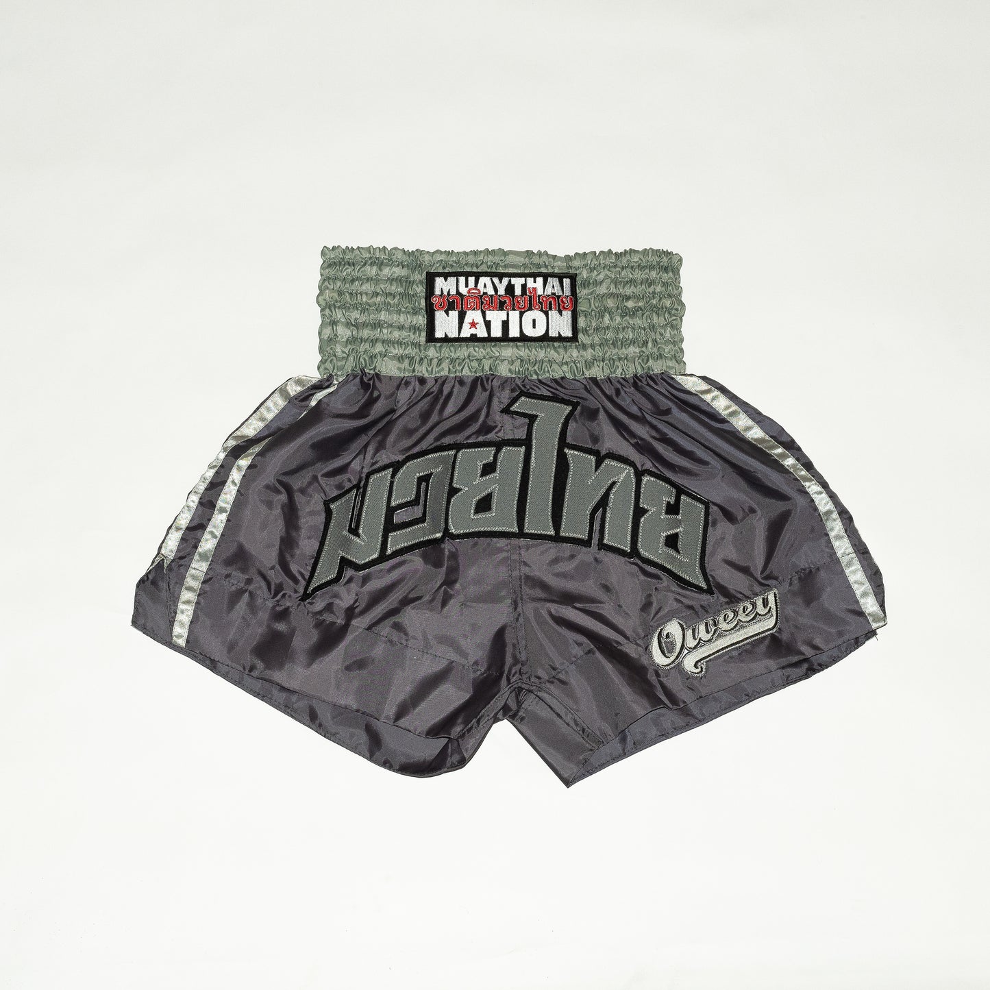 Gray Muay Thai shorts with branding on a light gray background