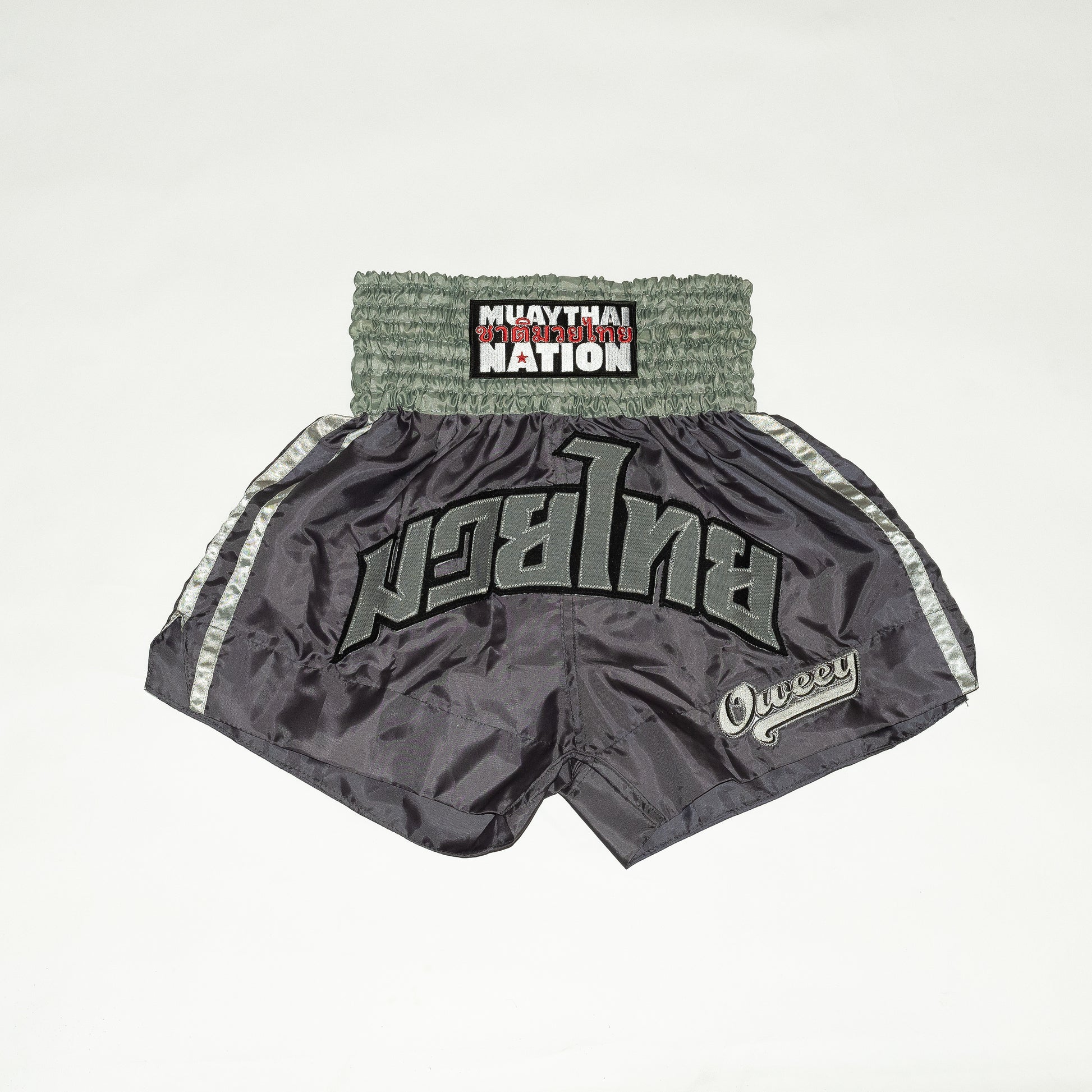 Gray Muay Thai shorts with branding on a light gray background