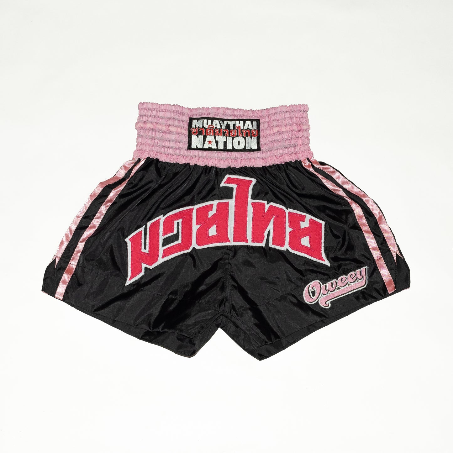 Black and pink Muay Thai shorts with visible branding on a white background