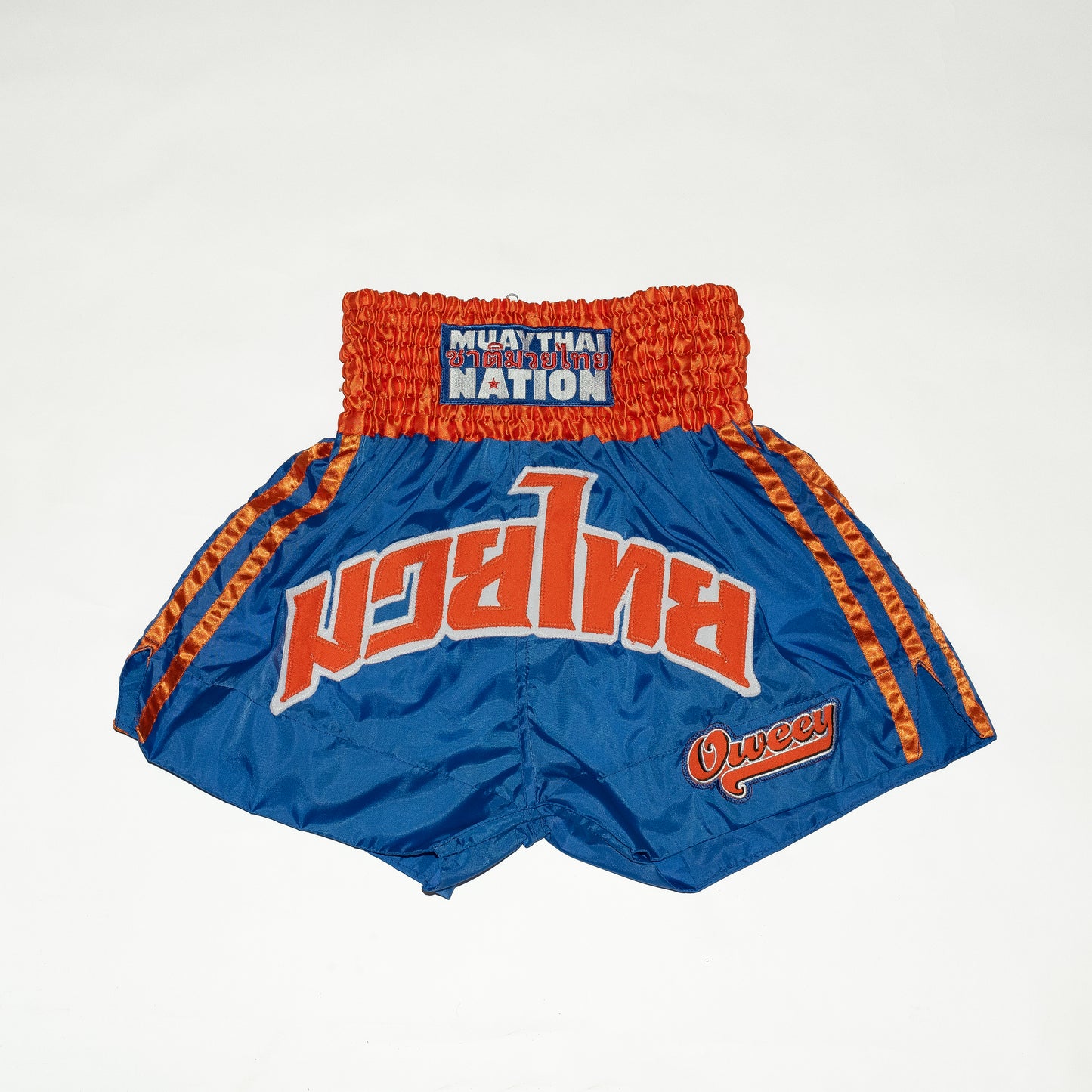 Blue and orange Muay Thai shorts with 'Muay Thai Nation' branding on a white background