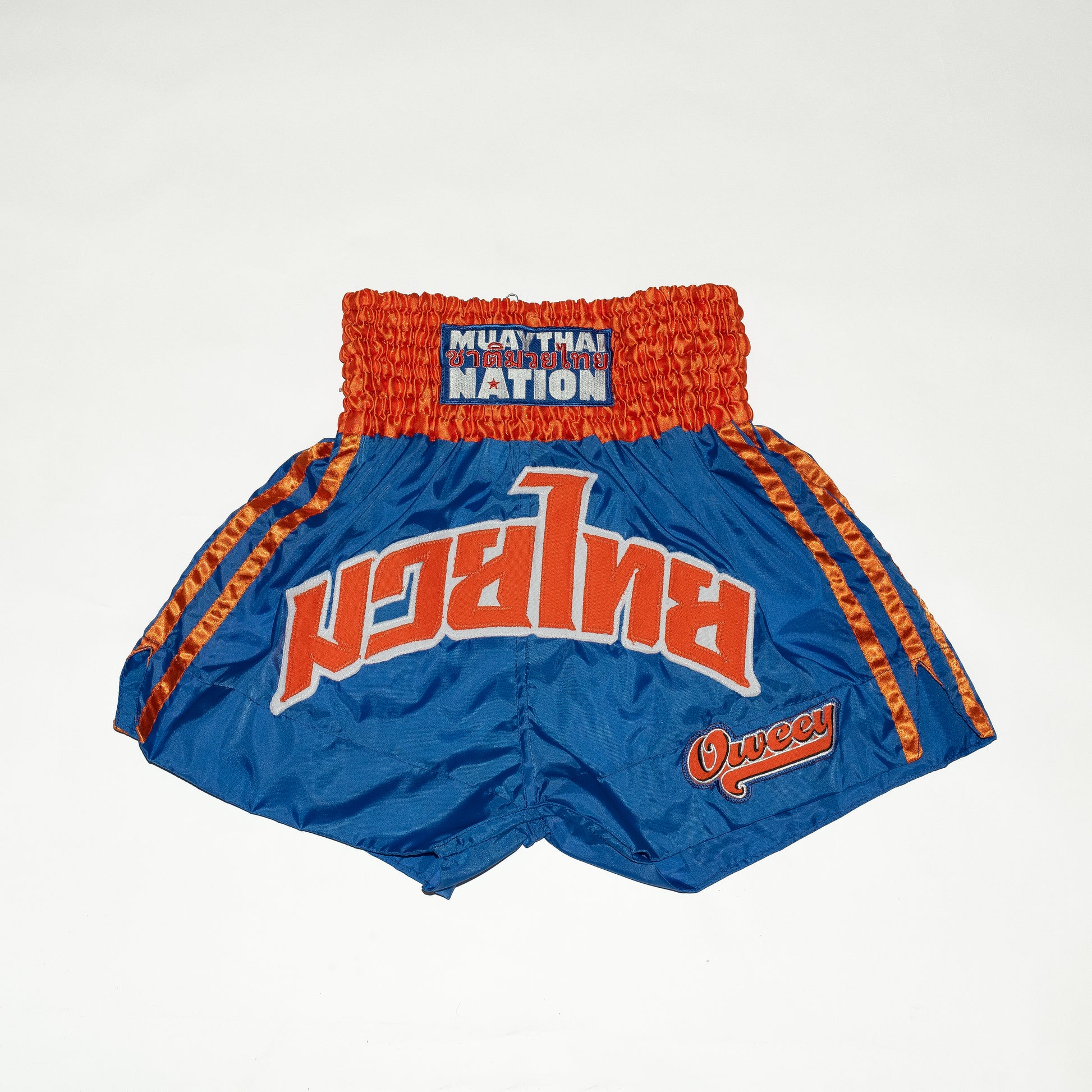 Blue and orange Muay Thai shorts with 'Muay Thai Nation' branding on a white background