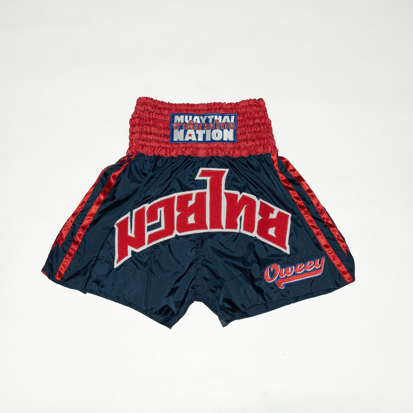 Navy blue Muay Thai shorts with red and white text on a white background