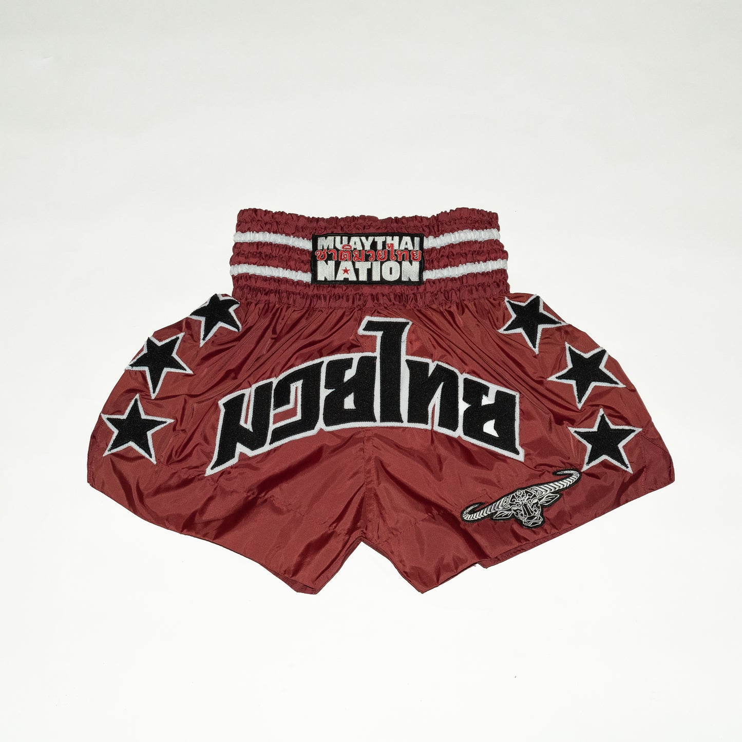 Red Muay Thai shorts with star patterns and 'Nation' branding on a white background