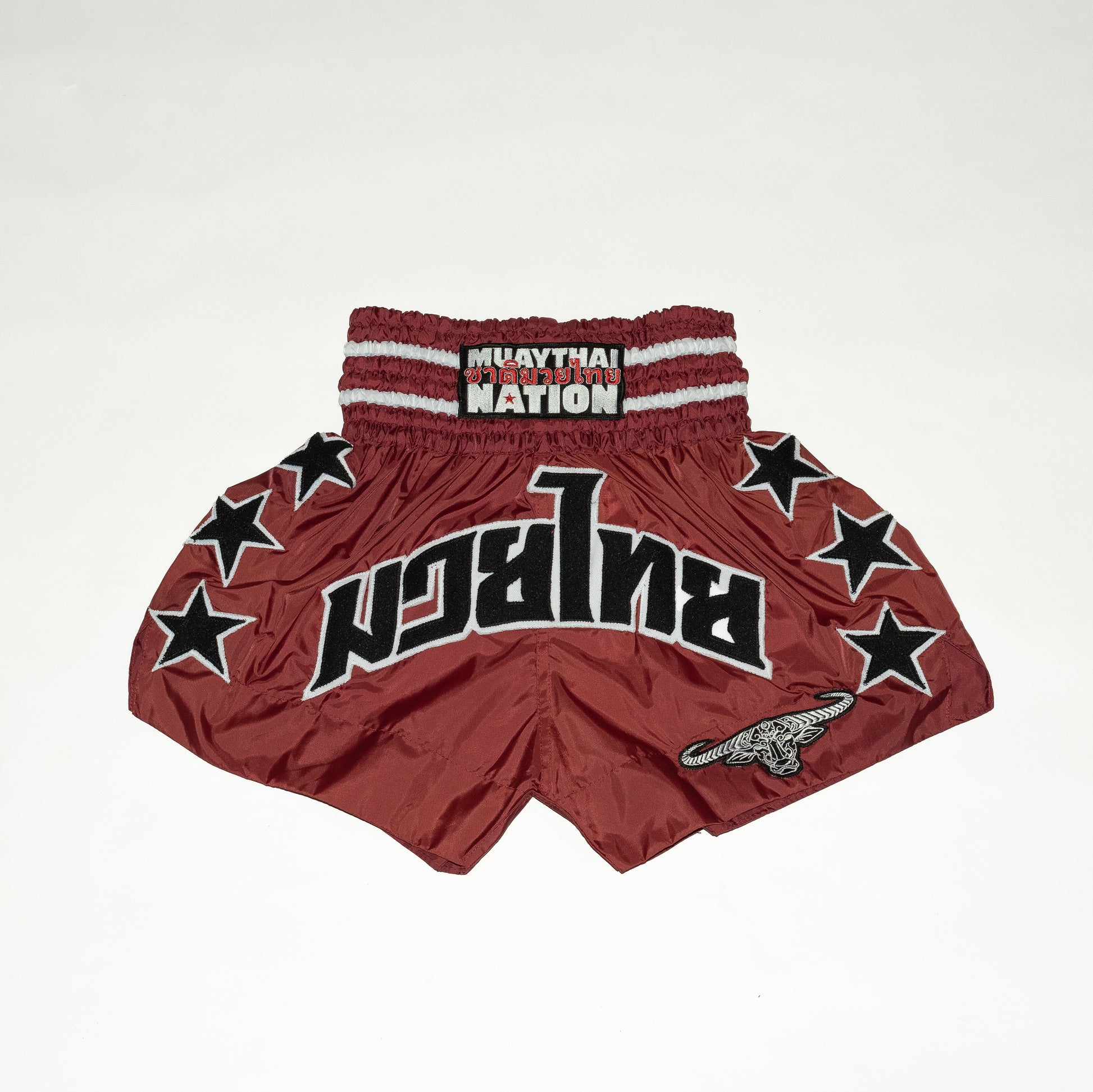 Red Muay Thai shorts with star patterns and 'Nation' branding on a white background