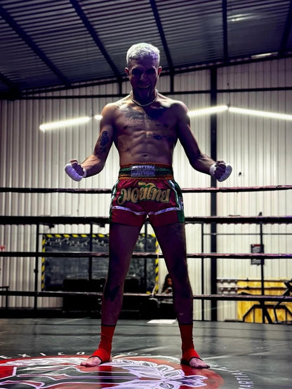 Professional Muay Thai fighter shouting in red shorts and guards