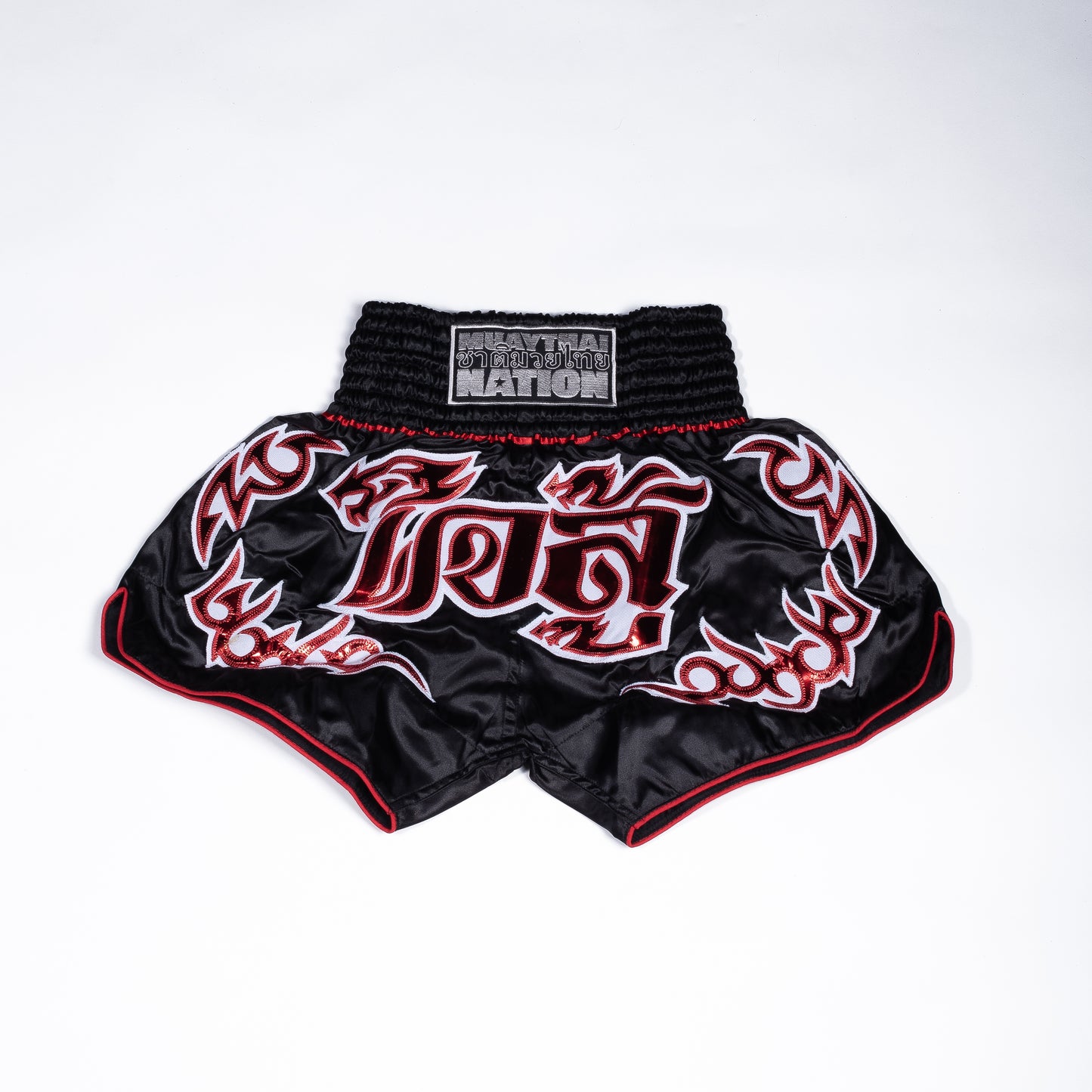  Muay Thai Nation standard black shorts with vibrant red flame side panelling.