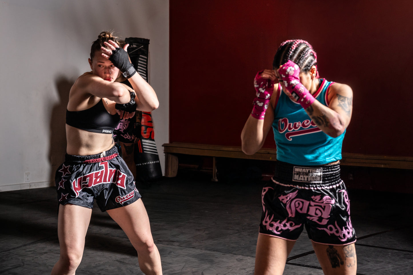 Women's Muay Thai shorts in black and pink during sparring practice.
