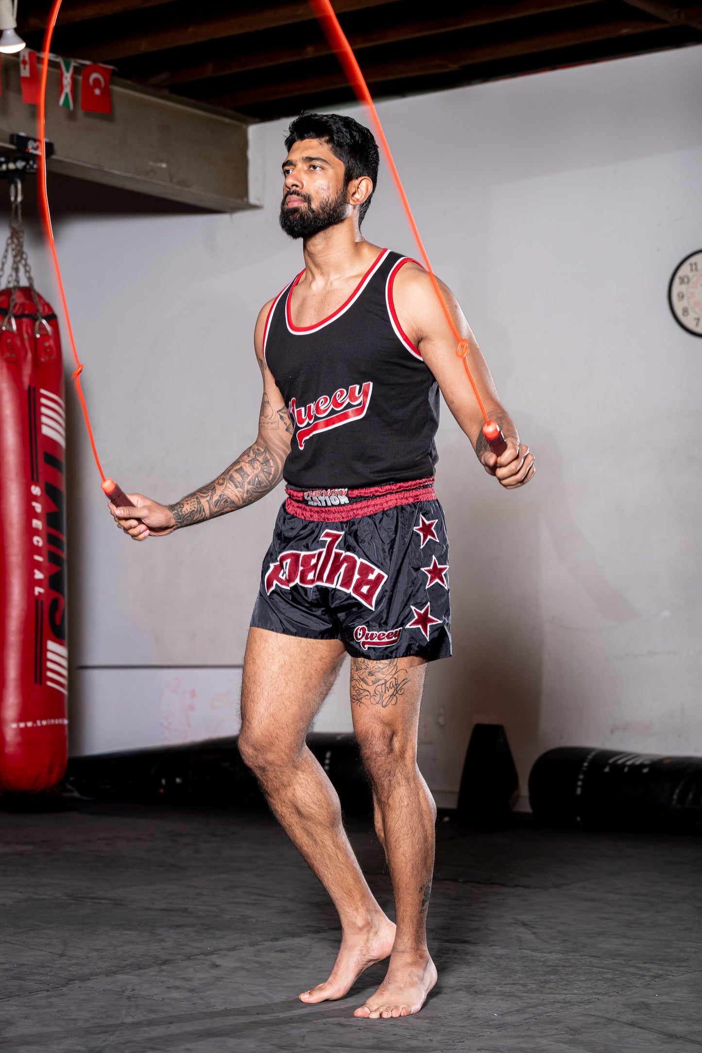 Black Muay Thai shorts with red star accents paired with a black oweey Muay Thai training tank.
