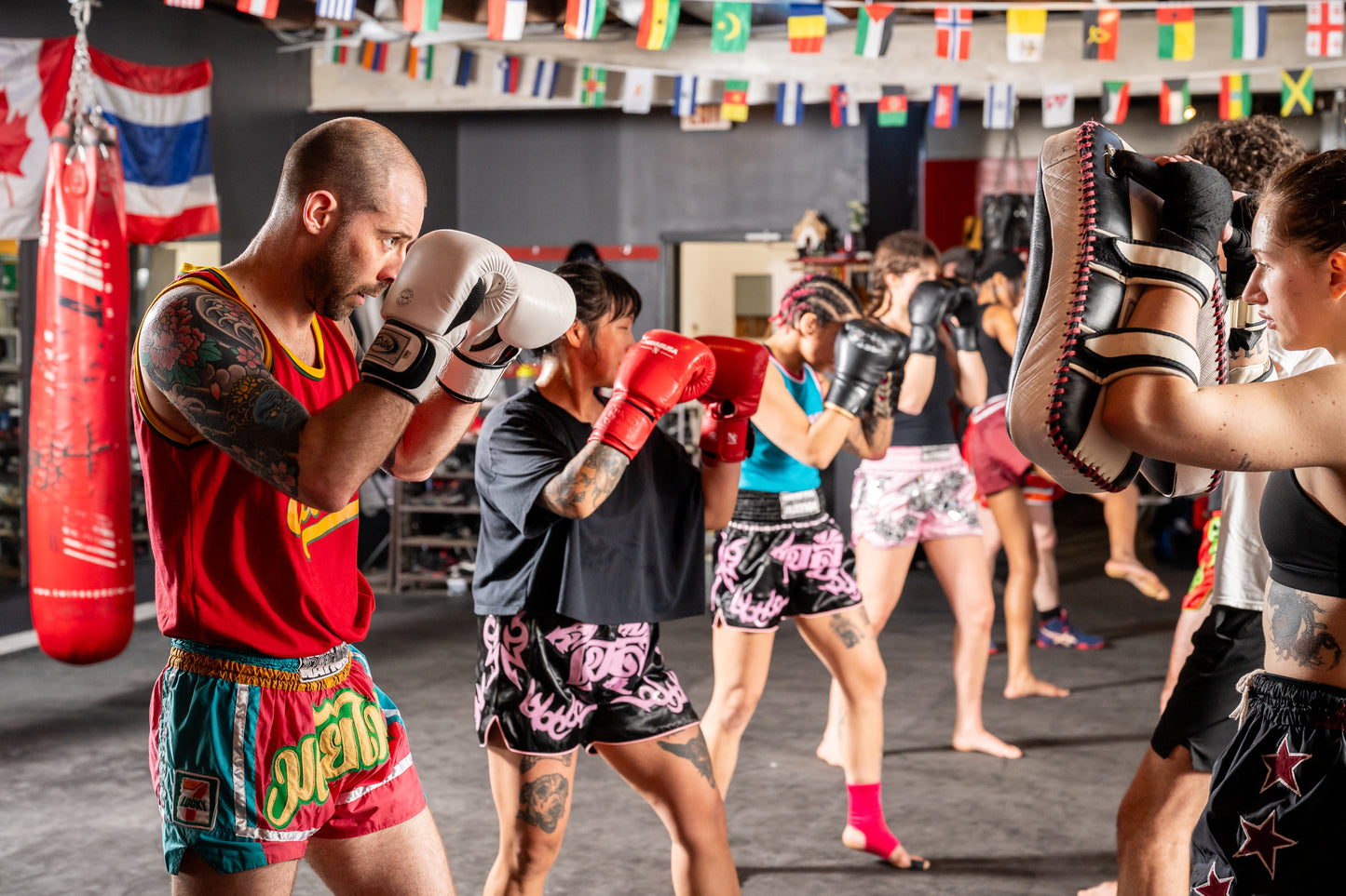 Muay thai fighters wearing red, green, black and pink shorts during pad training.