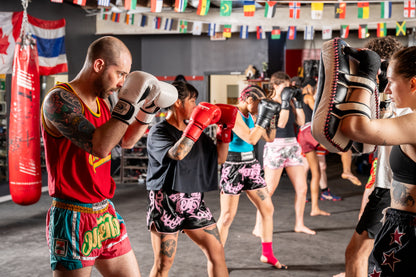 Muay thai fighters wearing red, green, black and pink shorts during pad training.